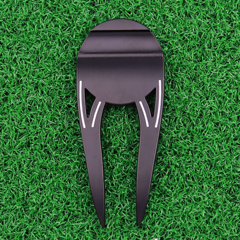 Black metal golf divot tool on green grass